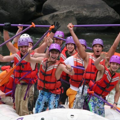 a group of people paddling down the rapids with a smile