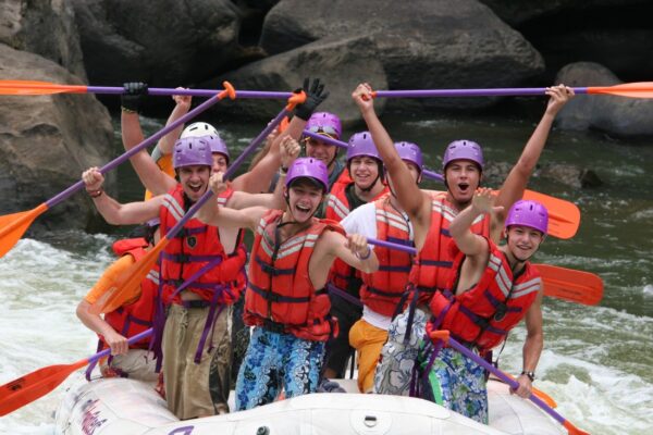 a group of people paddling down the rapids with a smile