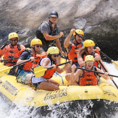 a group of people paddling down the rapids with a smile