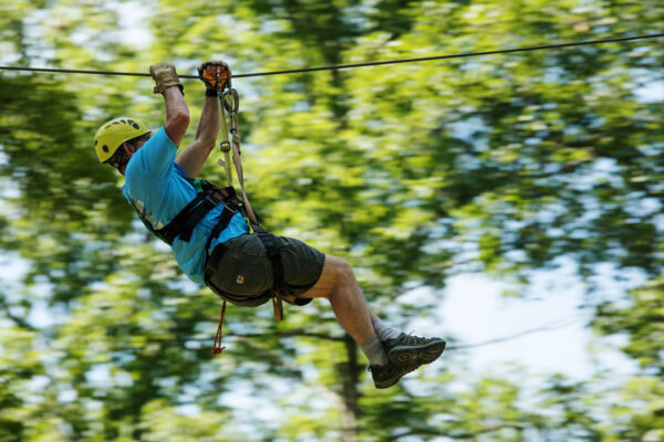 man ziplines through the trees at River Expeditions West Virginia