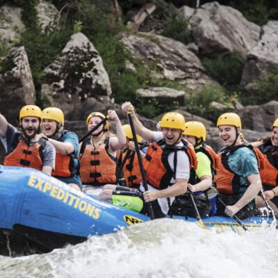 a group of people paddling down the rapids with a smile