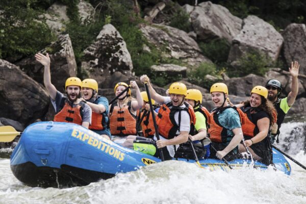 a group of people paddling down the rapids with a smile