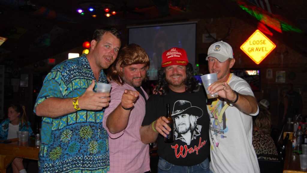 a group of people in 80s gear smiling with their drinks in hand