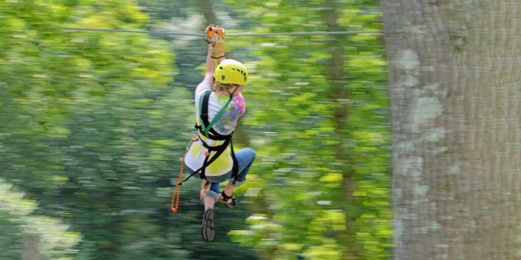 close up of woman doing zipline through the trees at River Expeditions West Virginia