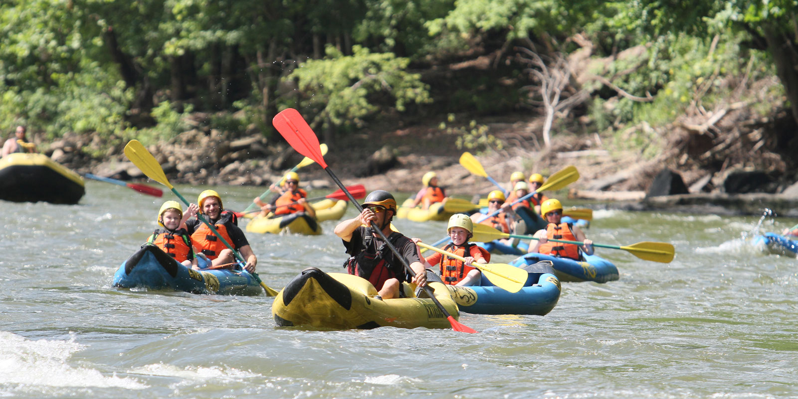 large group of individual rafters float down the calm river. River Expeditions West Virginia