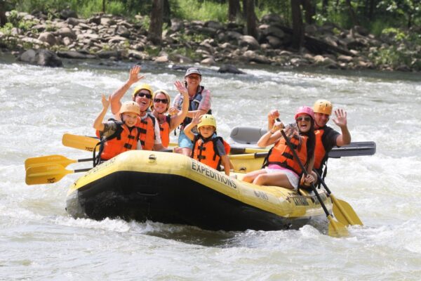 a group of people paddling down the rapids with a smile