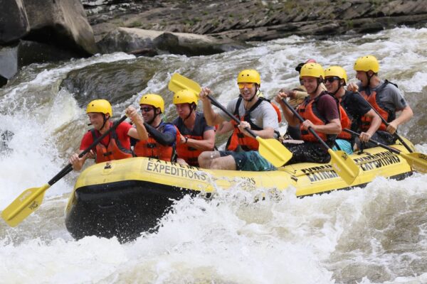 a group of people paddling down the rapids with a smile