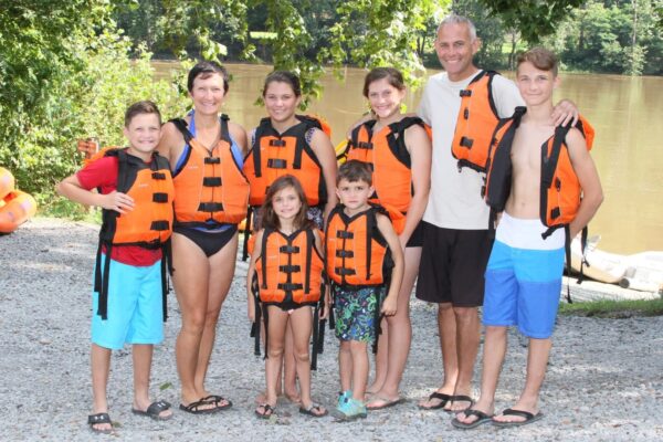 a family smiling in their lifejackets with the river in the background
