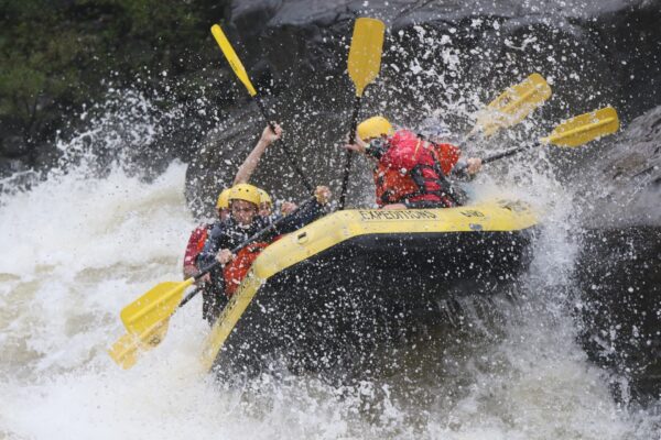 a group of people paddling down the rapids with a smile