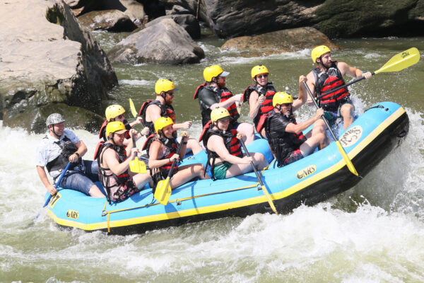 a group of people paddling down the rapids with a smile