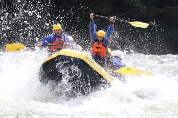 a group of rafters about to dip down into the water with smiles on their faces