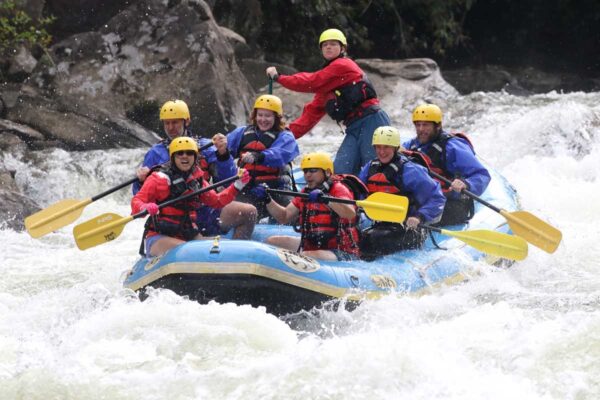 a group of rafters about to dip down into the water with smiles on their faces