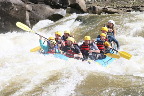 a group of rafters about to dip down into the water with smiles on their faces