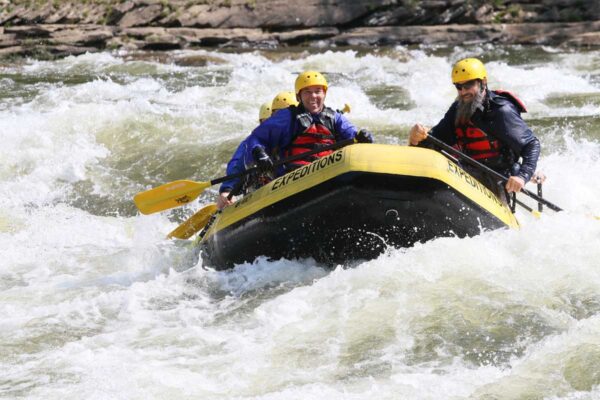 a group of rafters about to dip down into the water with smiles on their faces