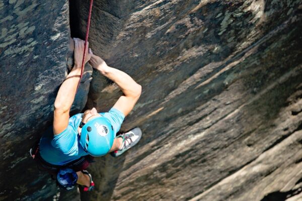 a man rockclimbing up a steep rock