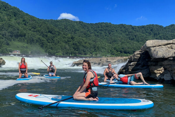 a group of stand up paddlers resting on the water