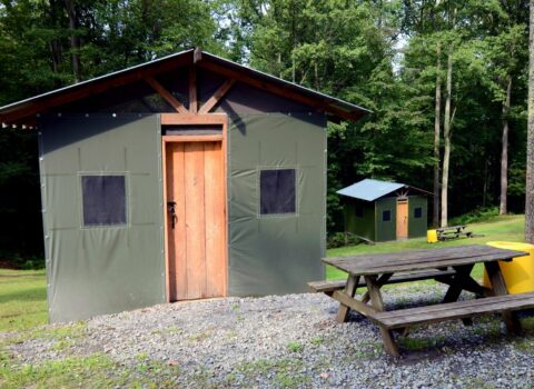 the outside of a safari tent with a picnic table in front