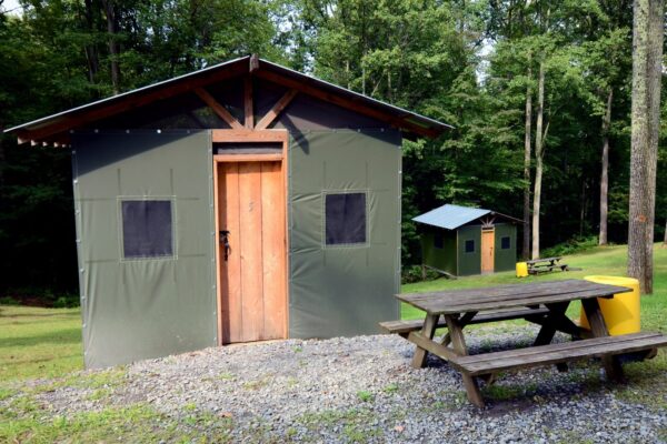 the outside of a safari tent with a picnic table in front