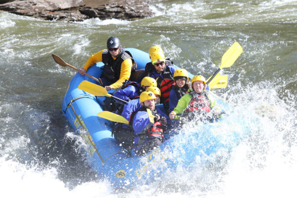 a group of people paddling down the rapids with a smile