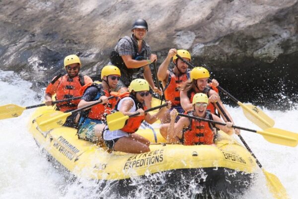 a group of people paddling down the rapids with a smile