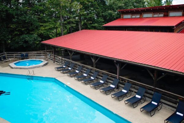 a pool and hot tub with lounge chairs and a building in the back