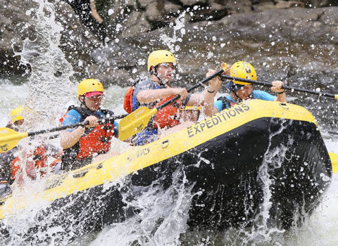 a group of people paddling down the rapids with a smile