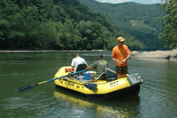 3 men in a raft fishing on calm waters