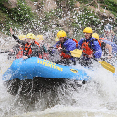 a group of people paddling down the rapids with a smile