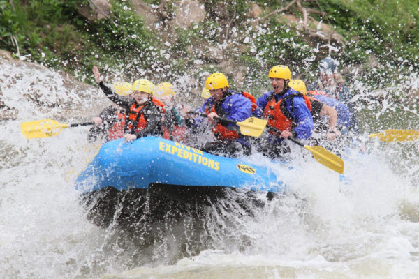 a group of people paddling down the rapids with a smile