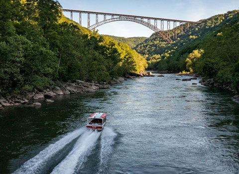 boat going under a bridge near sunset time River Expeditions West Virginia