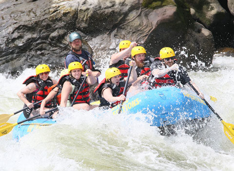 Whitewater rafters and guide work together to navigate past strong rapids. River Expeditions West Virginia