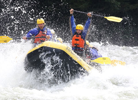 rafter holds his paddle up in victory after navigating through strong rapids. River Expeditions West Virginia