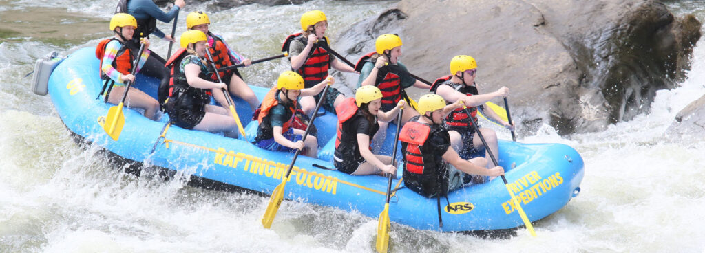 group of whitewater rafters avoid a big rock on the New River at River Expeditions West Virginia