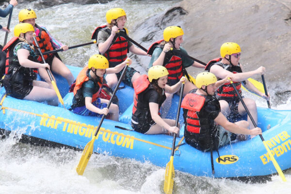 group of whitewater rafters avoid a big rock on the New River at River Expeditions West Virginia