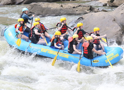 group of whitewater rafters avoid a big rock on the New River at River Expeditions West Virginia
