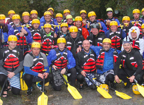 a group of rafters posing with their gear and paddles before hitting the water