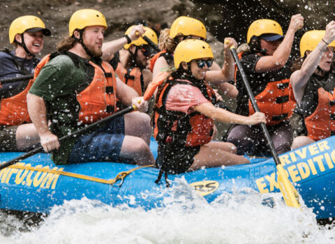 large group use paddles to navigate down the splashing rapids River Expeditions West Virginia