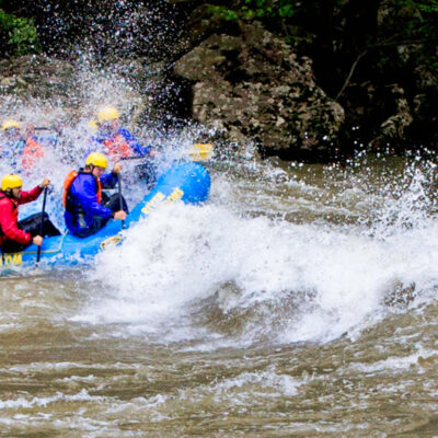 a group of people paddling down the rapids with a smile