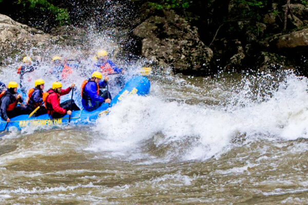 a group of people paddling down the rapids with a smile