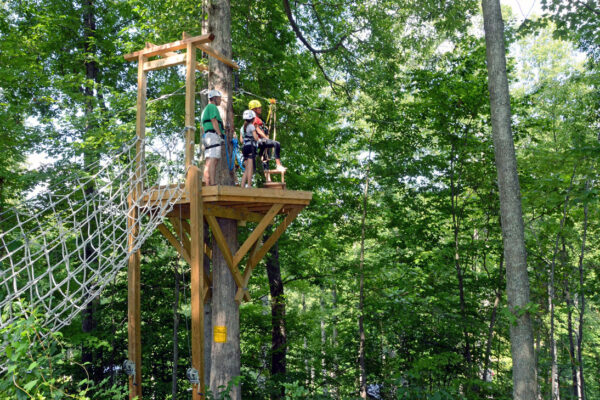 a group of people waiting on top of a platform to zipline