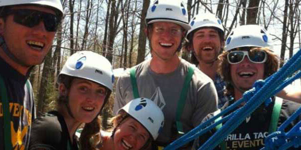 a group of people smiling attached to their ziplines